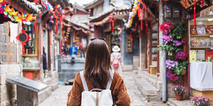 A tourist walking through a traditional street of China which is covered in vibrant paper decorations. 
