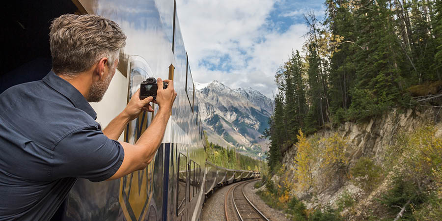 Man taking photo form Rocky Mountaineer Goldleaf outdoor platform